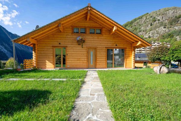 Lo Chalet del Franco: la casa in legno vista dal giardino, con il vialetto in pietra