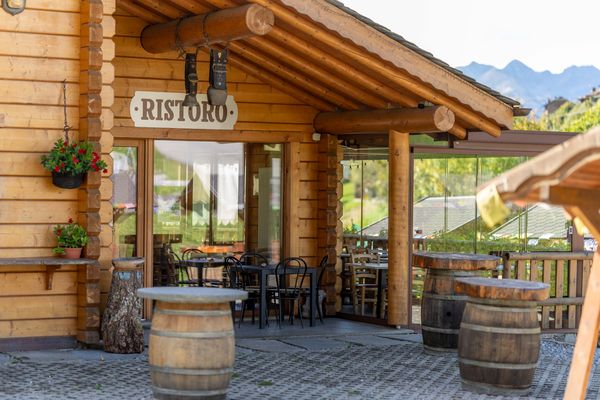 L’ingresso sotto il portico in legno con l’insegna Ristoro e le botti usate come tavolini