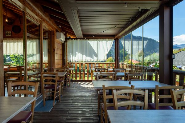 La veranda vetrata con i tavoli e la vista sulle montagne